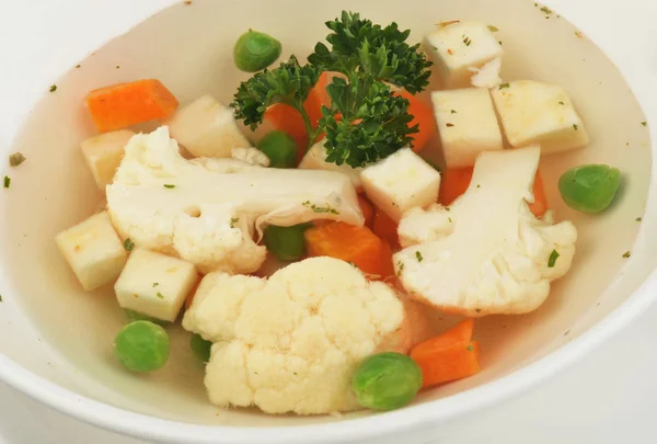 Vegetable soup with cauliflower, potatoes, peas, carrots and parsley on a white isolated background — Stock Photo, Image