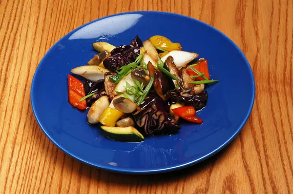Legumes cozidos no vapor com carne em uma placa azul em um fundo de madeira — Fotografia de Stock