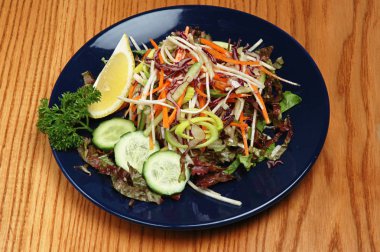 Ahşap bir arka plan üzerinde mavi bir tabaküzerinde buharda sebze