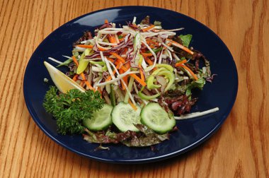 Ahşap bir arka plan üzerinde mavi bir tabaküzerinde buharda sebze