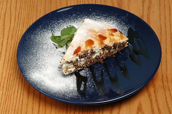 Pyszne kawałek ciasta na niebieskim talerzu z wystrojem. Na drewnianym tle. Jedzenie w restauracji. — Zdjęcie stockowe