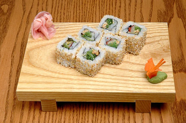 Sushi sur un support en bois, wasabi et gingembre mariné. Sur fond en bois — Photo