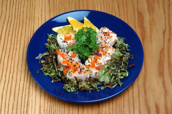 Mavi plaka üzerinde limon ve maydanoz ile deniz ürünleri tabağı