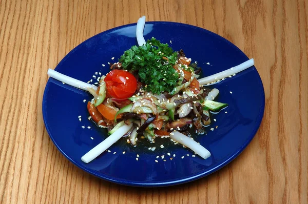 Ahşap bir arka planda mavi plakalı et ile buharda sebze