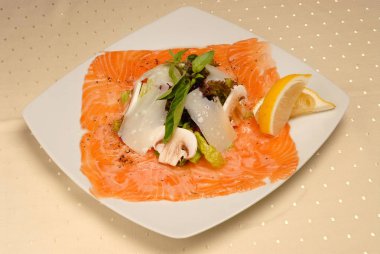 Beyaz izole arka planda bir kare plaka üzerinde zeytin ve limon ile sebze ve deniz ürünleri salata