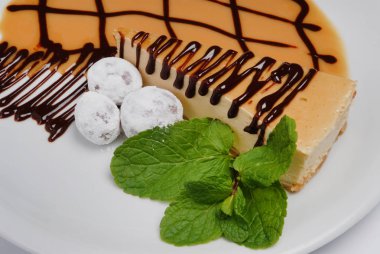 Gri bir arka plan üzerinde bir tabak üzerinde nane yaprakları ile Cheesecake