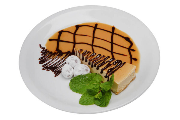 Cheesecake with mint leaves on a plate on a white isolated background