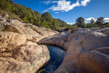 Fuente Caputa 'nın kaynağının yatay fotoğrafı, kayaların arasında, Mula kasabasında, Murcia bölgesinde, kayaların arasında ve güneşli bir günde