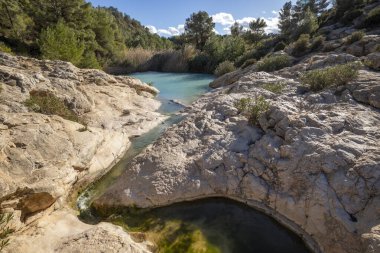 Fuente Caputa 'nın kaynağının yatay fotoğrafı, kayaların arasında, Mula kasabasında, Murcia bölgesinde, kayaların arasında ve güneşli bir günde