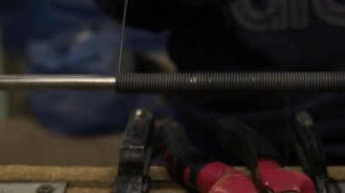 Çalışan bir metal çubuk bir tel yapar. Atölyesinde işçiliği