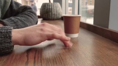 Café'de bekleyen kazaklı genç adam. Yandan yakından göz masaya vurmak.