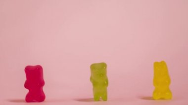 Sosyal uzaklık kavramı. Jelibon ayılar pembe arka planda hareket ediyorlar. Jöleli şekerler. Hareketi durdur 