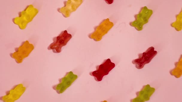 カラフルなグミはピンクを背景にしています 動きゼリーキャンディーを停止します お菓子業界 — ストック動画