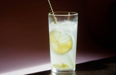 Bardakta buzlu limonata. Yaz ferahlatıcı içecek. Limon kabuğu ve zencefil kökü. Ahşap masa arka planı