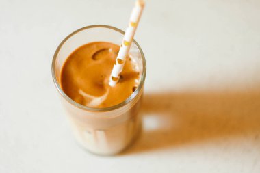 Kağıt kamışlı Dalgona kahvesi. Kağıt arkaplanda moda içki. Soğuk kokteyl. Kremalı kahve.