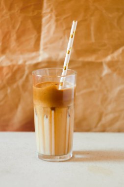 Kağıt kamışlı Dalgona kahvesi. Kağıt arkaplanda moda içki. Soğuk kokteyl. Kremalı kahve.