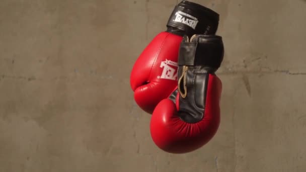 红色拳击手套挂在混凝土背景上 竞技体育标志 — 图库视频影像