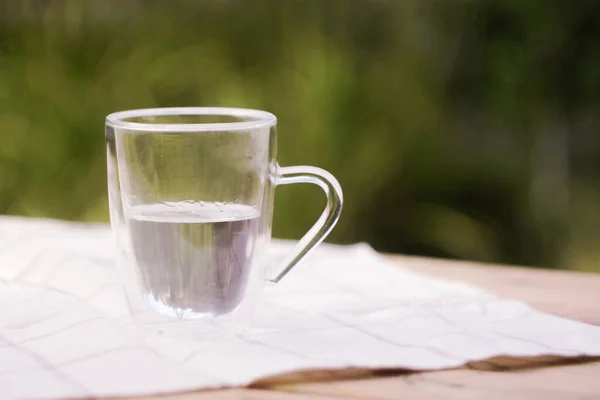 Tazza Trasparente Con Acqua Sul Tavolo Sfondo Verde Giardino Copia — Foto Stock