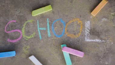 Okul afişine dönelim. Renkli tebeşirle yazılmış bir kelime. Çocuk çizimleri. 