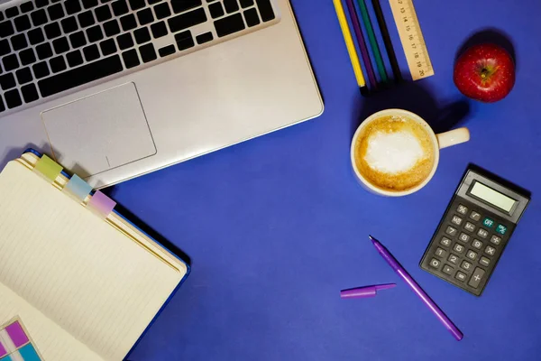 Flat lay. Student desk. Business school. Office job concept. Classic blue background. Paper work. Cup of coffee. Notepad and stationary. Freelancer workplace
