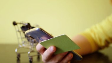Kredi kartıyla internetten satın almak. Akıllı telefonu tutuyorsun. Çantalı alışveriş arabası. İnternetteki mağaza. Kara Cuma indirimi. Boşluğu kopyala