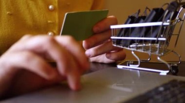 Klavyeye kredi kartı kodu yazan bir kadın. Siyah çantalı alışveriş arabası. İnternetteki mağaza. Kara Cuma. Son satış. E-ticaret kavramı