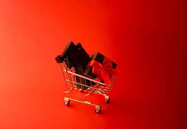 Hediye paketi alışveriş arabasında. Maytap bulanık. Kırmızı arka plan. Yeni Yıl Kutlaması