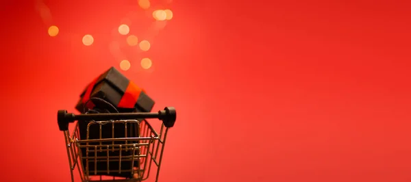 ギフトボックスバナー付きショッピングカート 新年割引 お祝いのライトが点滅 赤の背景 スペースのコピー — ストック写真