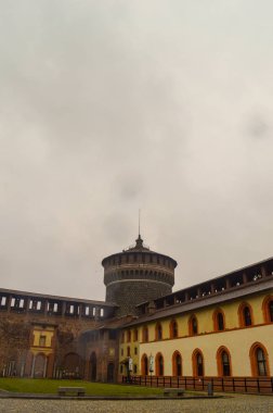 Bir castle izle kuleye bulutlar ve sarı binalar ile yağmurlu bir bakış