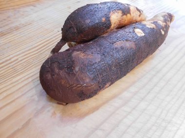 Doğrama kurulu üzerinde iki tatlı manyok kökleri. Bu gıda da adları yucca, mandioca, maniot, manyok, PARI, quiv, yuca brava, yuca amarga, mandioca ve Brezilyalı ararot tarafından gider. Onların koyu kahverengi dış ince tabaka deri sıyırma başlar. 