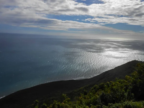 Hill, dik yokuş aşağı cliff düşük topraklara seafront adlı tepesinden. Koyu mavi gölgeli su deniz ışık dalgaları dalgalanan hafifçe ağrıyan için taşır. Yukarıdaki ve bölünmüş ufuk tarafından bulutlu mavi gökyüzü uçsuz bucaksız Okyanusu gölgelerde döküm olduğunu..