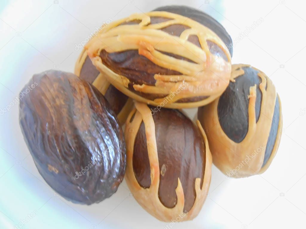 Group of nutritious, spicy, nutmegs in shell and mace covered except for one. Nutmeg, seed or fruit of the Myristica fragrans tree is popular for the two ground spices derived from its fruit. 