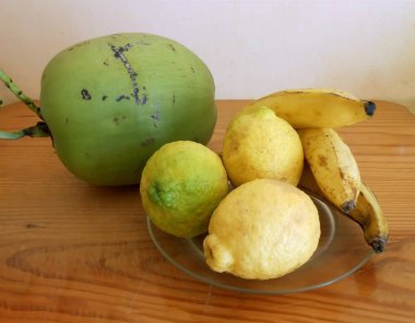 Bir eski parlak Doğrama tahtası üzerinde parlak kahverengi tahıl, çentikler ve chop işaretleri ile bir yeşil doğal organik gıdalar vardır renk Hindistan cevizi ve üç her içeren bir şeffaf plaka sarı limon ve muz.