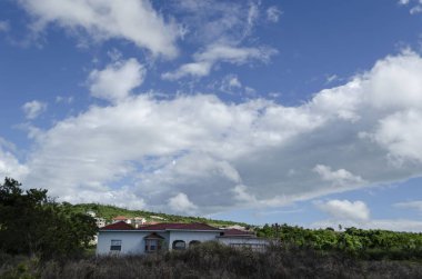 Manzara görünür güneş ışığı uzaktan görülür iken gölge arazi parçası üzerinde döküm kısmen bulutlu gökyüzü. Büyük beyaz bulutlar yamalari ile parlak mavi gökyüzü. Dünya yüzeyinde evleri ve yeşil yemyeşil bitki örtüsü ile kaplıdır.