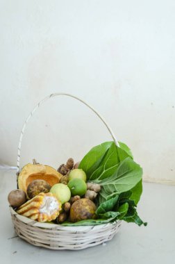 Beyaz bir yüzeyde yeşil olgun beyaz bir plaka, ve sarı olgun anahtar kireç, sarı olgun haziran erik, turuncu olgun calabaza kabak, yeşil ve beyaz pak choi bir baş, bir cob sarı mısır soyulmuş ve çöp mısır bir yarısı vardır.. 
