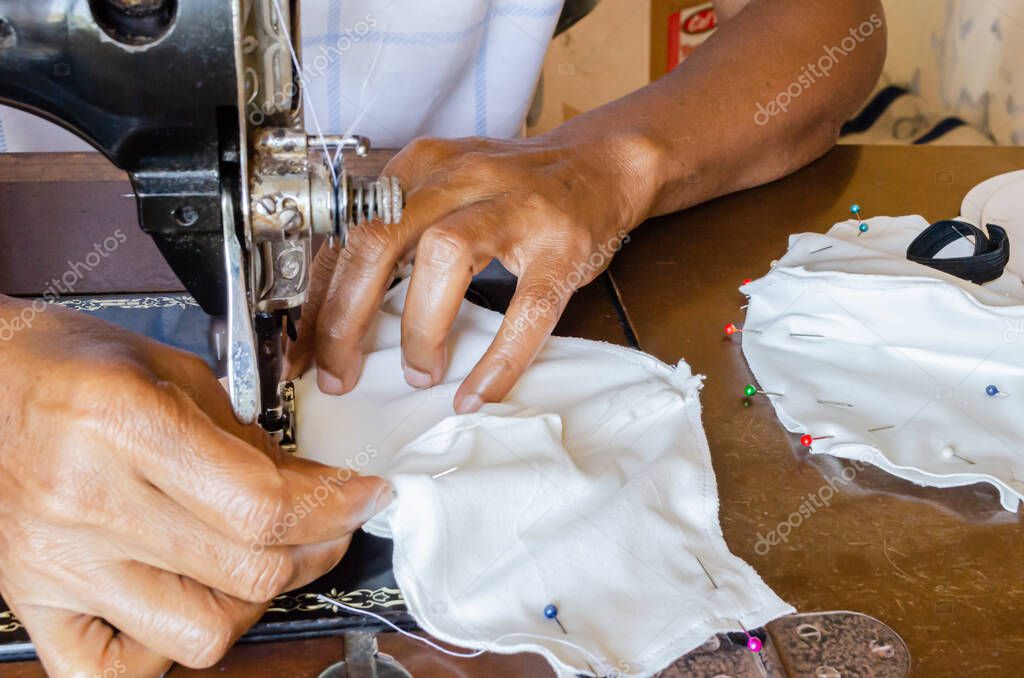 Con una mano agarrando la tela detrás del prensatelas, y la otra en la parte delantera, una