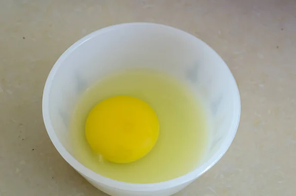 在一个小白盘里 有一只鸟蛋的浓郁的黄色蛋黄和淡黄的蛋白 — 图库照片