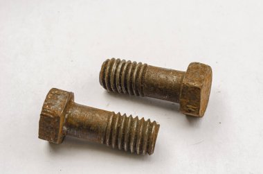 Paslı civataların beyaz arka plana yakın görüntüsü kalın düz başlarını dar iplik açılarını ve düz uçlarını gösteriyor.