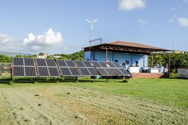 To generate electrical energy, a small twelve-panel solar unit in which the panels turn as the sun moves, is installed on an open area of green groomed grass lawn. To support, and increase the generating capacity a small wind turbine is also added.