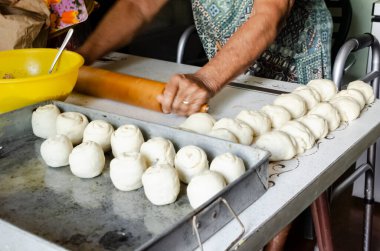 Son sınıf öğrencisi bir bayan, hindistan cevizini katlayıp şekerli çörek yapmak için kullandığı hamuru yassılaştırmak için merdane kullanıyor. Hareket kabiliyetini dengelemek için yürüteç kullanıyor..