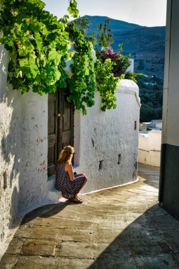 Bu resmi bir adım son akşam güneş zevk bir Yunan köyde oturan bir kadın vardır. Üzüm asmaları yukarıda asılı eski bir ahşap kapı infront olan