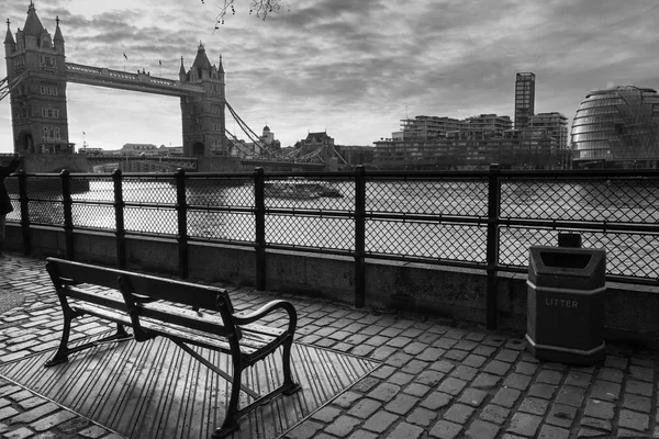 一张黑白相间的长椅照片 望着泰晤士河 背景中有塔桥 — 图库照片