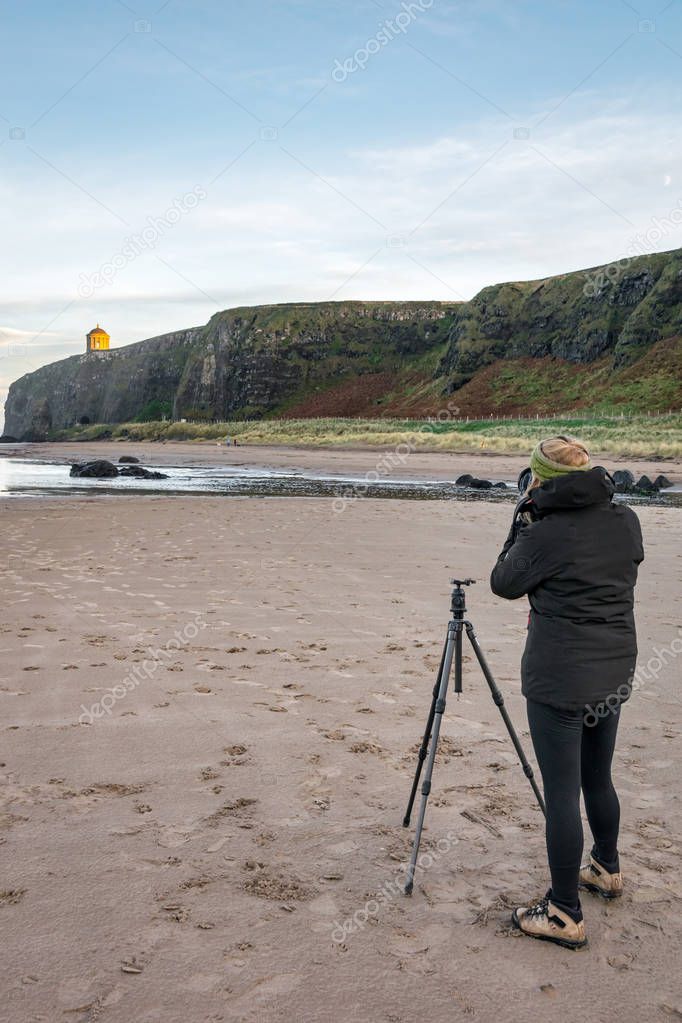 This is a picture of a photographer taking a landscape photo on a beach in Ireland