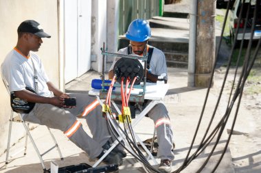 Fiber optik internet işçileri yerleşim yerindeki bir sokakta yeni bir kabloyu bağlıyorlar.