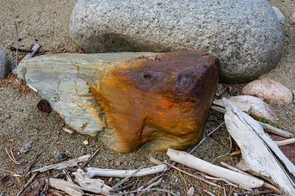 Két kő fekszik a homokos parton fával. — Stock Fotó