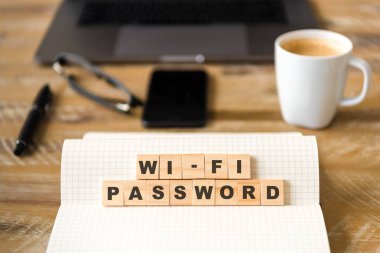 Closeup ahşap masa arka plan üzerinde dizüstü WiFi şifre kelime yapma harflerle ahşap bloklar üzerinde odaklanın. İşletme kavramı resmi. Dizüstü bilgisayar, gözlük, kalem ve ufuk arka plan içinde hareket eden telefon.