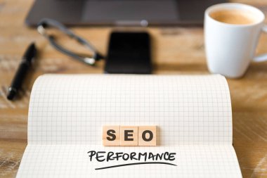 Dizüstü üzerinde ahşap masa arka plan, closeup Seo performans metin yapma harflerle ahşap bloklar üzerinde odaklanın. İşletme kavramı resmi. Dizüstü bilgisayar, Gözlük, kalem ve cep telefonu ufuk arka planda