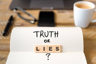 Closeup dizüstü vintage Resepsiyon yüzeyi üzerinde ön ahşap bloklar odaklanmak Truth or Lies metin yapma harflerle. İşletme kavramı resmi office araçları ve kahve fincanı arka planda