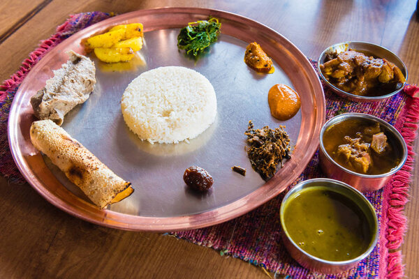 Top view over Dal bhat plate, a traditional meal from the Indian subcontinent, popular in many areas of Nepal, Bangladesh and India. It consists of steamed rice and a cooked lentil soup called dal.
