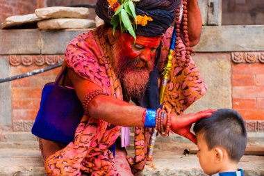 Pashupatinath, Nepal - 17 Temmuz 2018: Kutsal Sadhu adam geleneksel boyalı yüz ve colouful giysileri ile Pashupatinath, ünlü ve Kutsal Hindu Tapınağı Nepal'de karmaşık bir çocuğa nimet